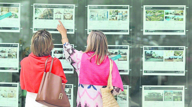 Dos personas consultan los anuncios de una inmobiliaria.