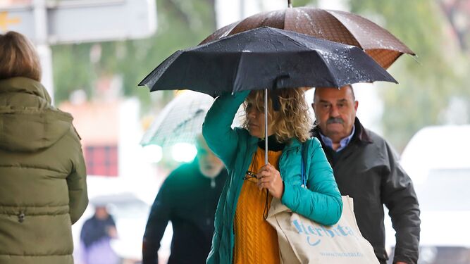 Dos personas se protegen de la lluvia con sus paraguas en Huelva.